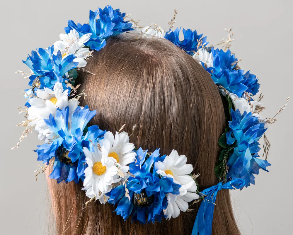 Mākslīgs vainags ar zilām rudzupuķēm un baltiem ziediem, un dabīgām smilgām
