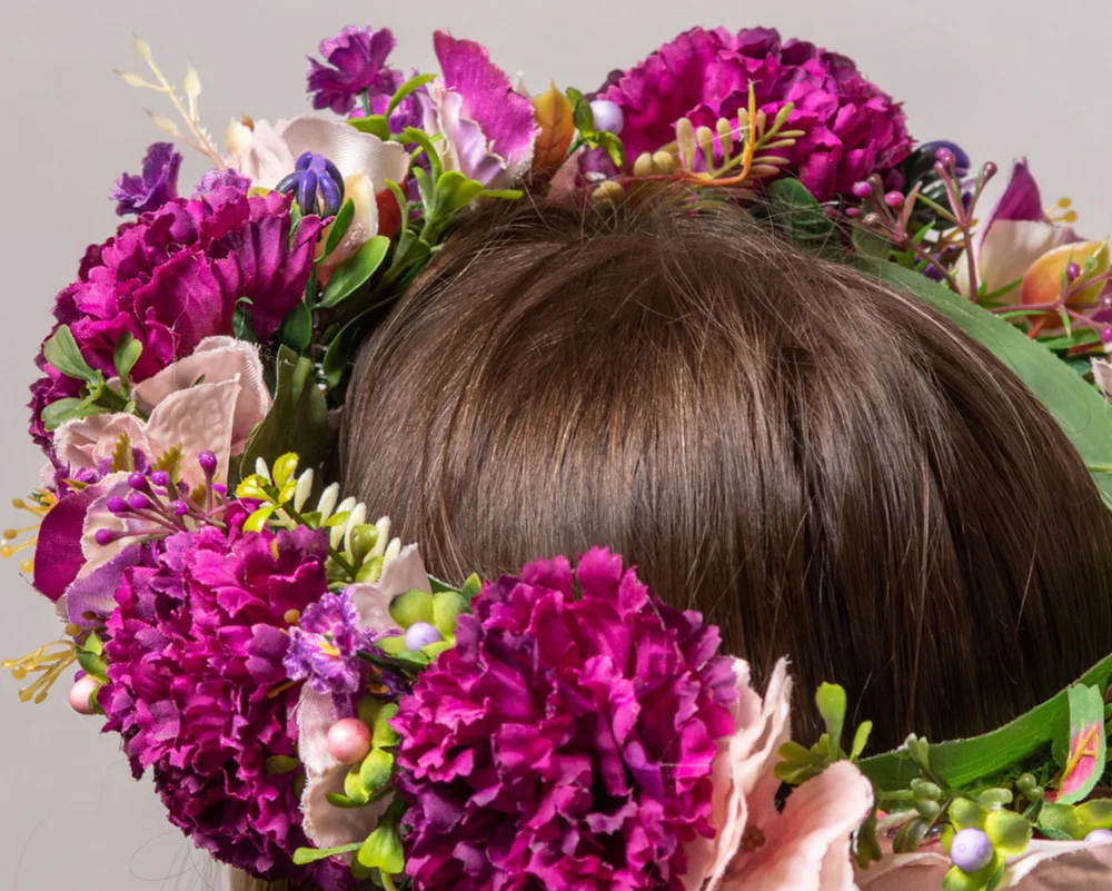 Bilde tuvplānā: mākslīgs vainags ar violetiem ziediem un zaļumiņiem