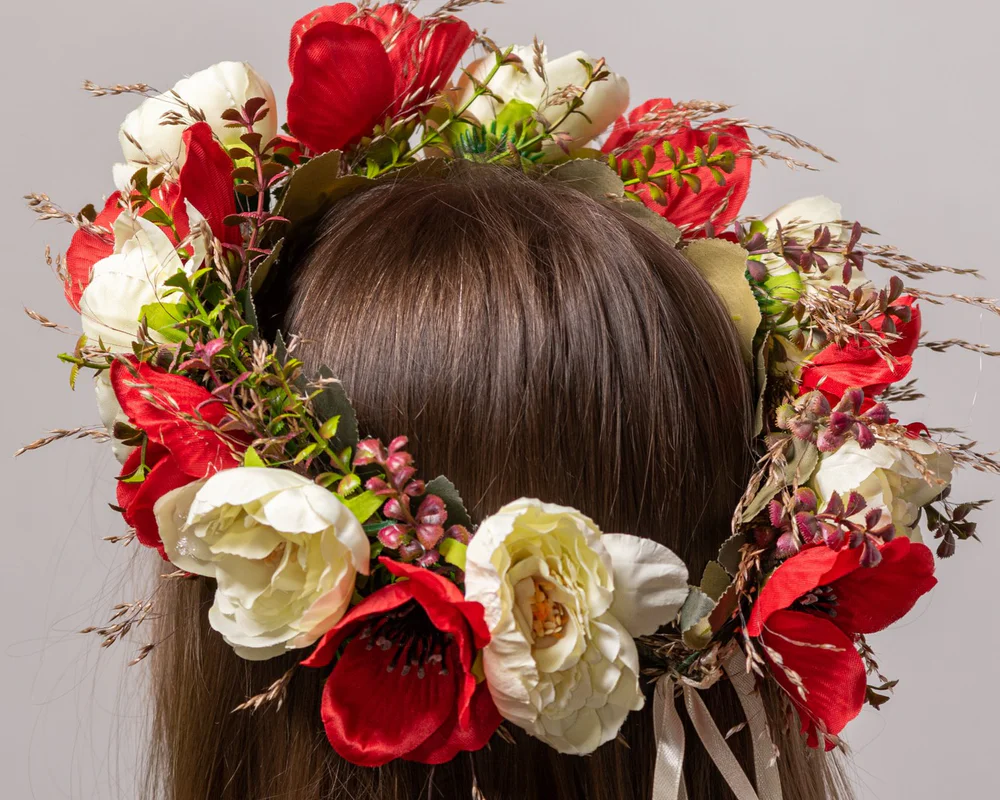 Mākslīgs vainags ar gaišiem un sarkaniem ziediem.